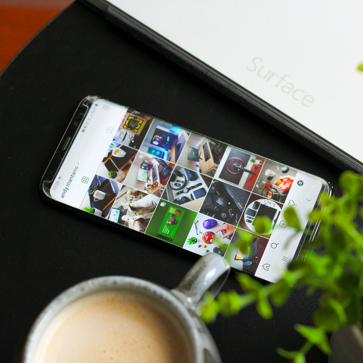 Smartphone en tablet op een bureau met koffie en planten.